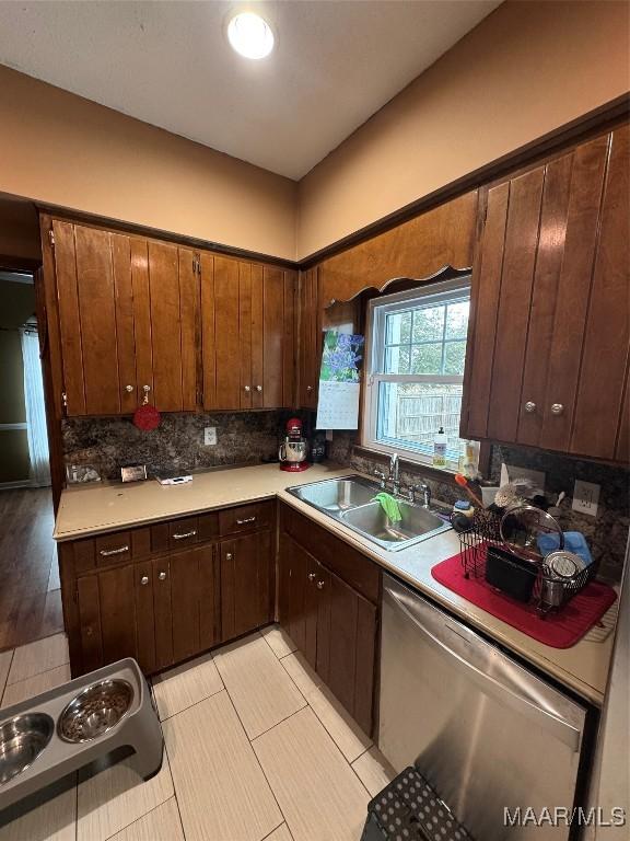 kitchen featuring dark brown cabinetry, sink, decorative backsplash, and stainless steel dishwasher