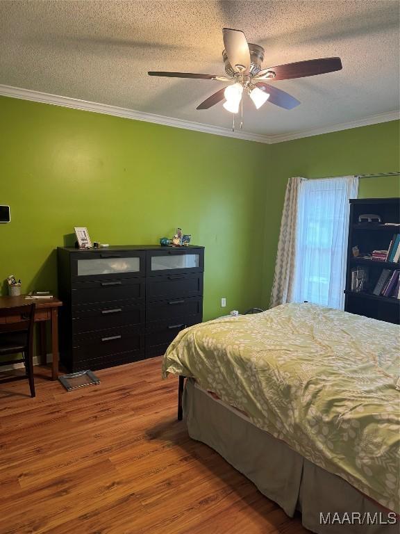 bedroom with ornamental molding, hardwood / wood-style floors, a textured ceiling, and ceiling fan