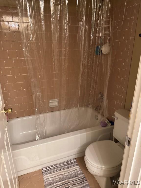 bathroom featuring shower / tub combo with curtain, tile patterned floors, and toilet