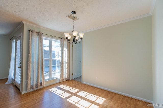 unfurnished dining area featuring crown molding, a textured ceiling, light hardwood / wood-style flooring, and a notable chandelier