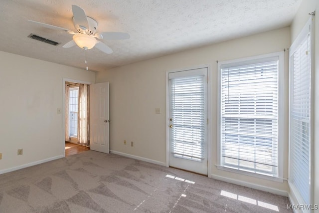 carpeted empty room with ceiling fan and a textured ceiling