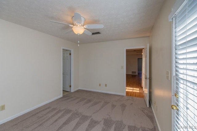 spare room with light colored carpet, a textured ceiling, and ceiling fan