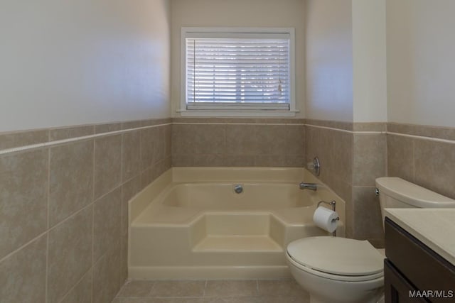 bathroom with tile patterned flooring, tile walls, a bathing tub, vanity, and toilet