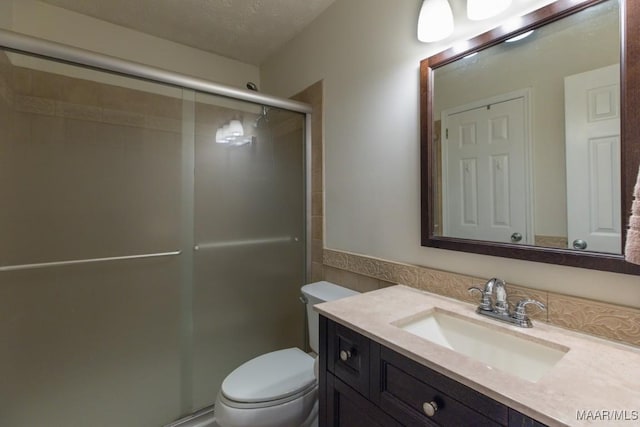 bathroom featuring an enclosed shower, vanity, toilet, and a textured ceiling