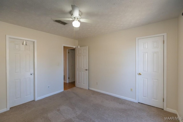 unfurnished bedroom featuring ceiling fan, light colored carpet, and a textured ceiling