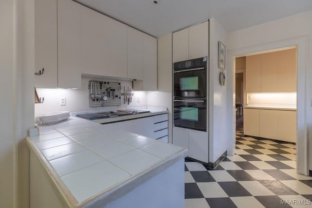 kitchen featuring white cabinetry, tile countertops, and black appliances