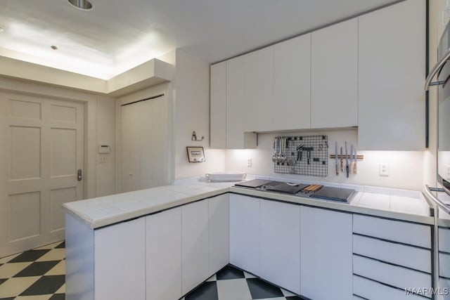 kitchen with black electric cooktop, kitchen peninsula, and white cabinets