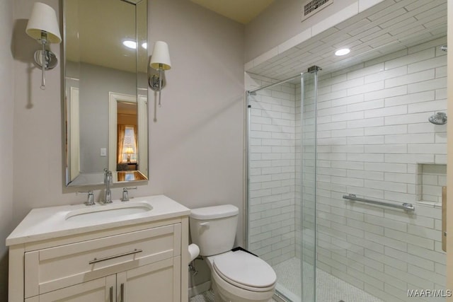 bathroom with vanity, a shower with door, and toilet