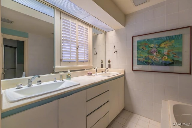 bathroom featuring tile patterned flooring, vanity, a bathing tub, and tile walls