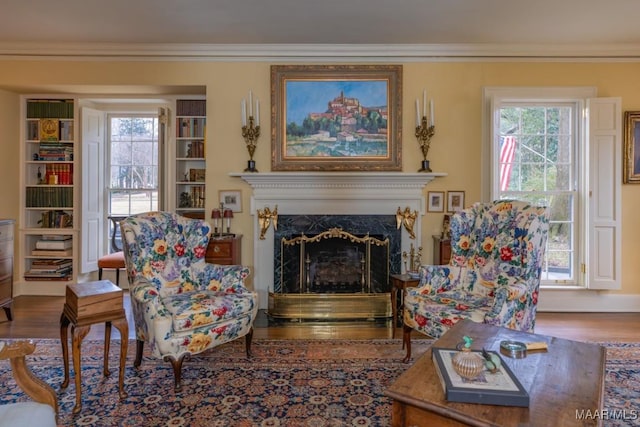 sitting room with hardwood / wood-style flooring, ornamental molding, and a premium fireplace