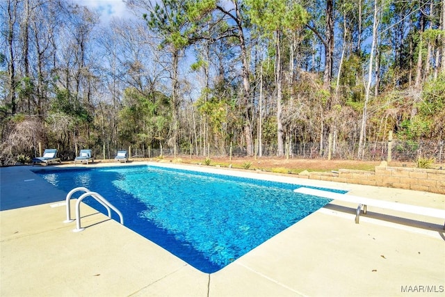 view of swimming pool featuring a diving board and a patio area