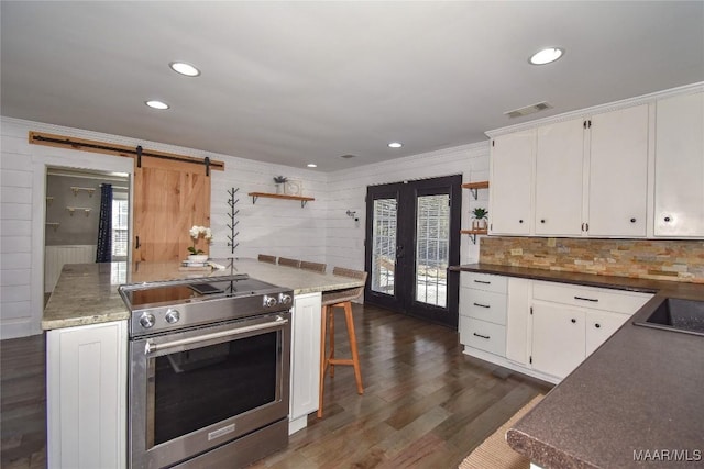 kitchen featuring crown molding, high end stainless steel range oven, a barn door, and white cabinets