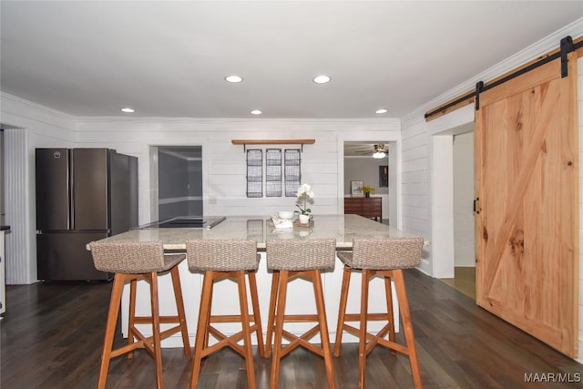 kitchen featuring dark hardwood / wood-style floors, a breakfast bar area, fridge, light stone counters, and a barn door