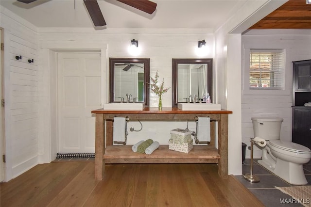 bathroom featuring hardwood / wood-style floors, toilet, ceiling fan, and wood walls