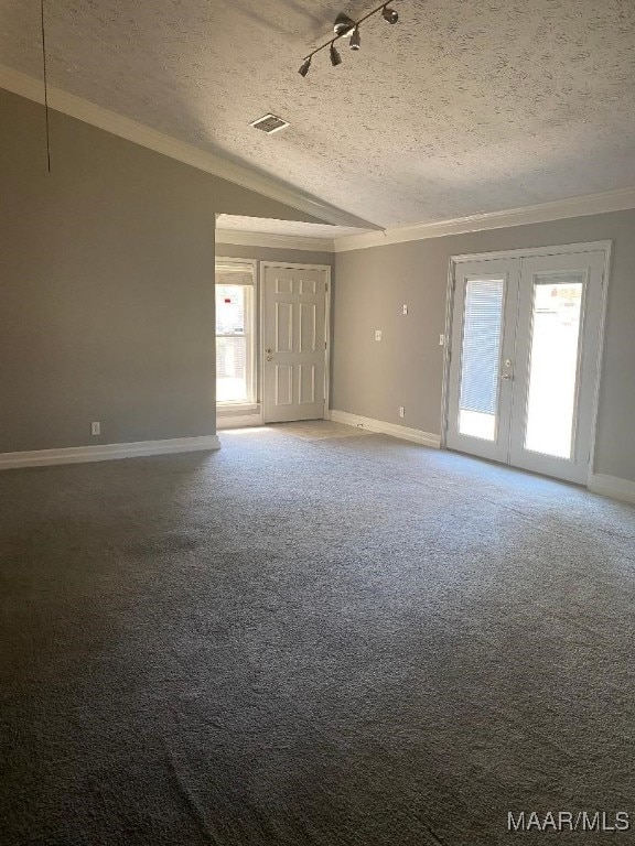 spare room featuring vaulted ceiling, rail lighting, carpet flooring, a textured ceiling, and french doors