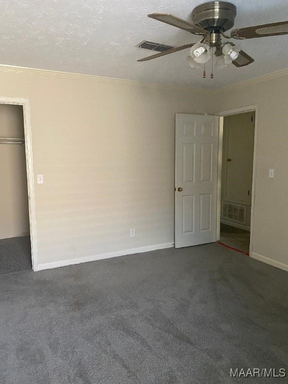 unfurnished room featuring ornamental molding, a textured ceiling, and dark colored carpet