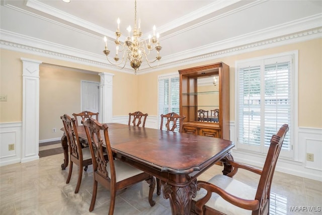 dining room featuring crown molding, an inviting chandelier, and ornate columns