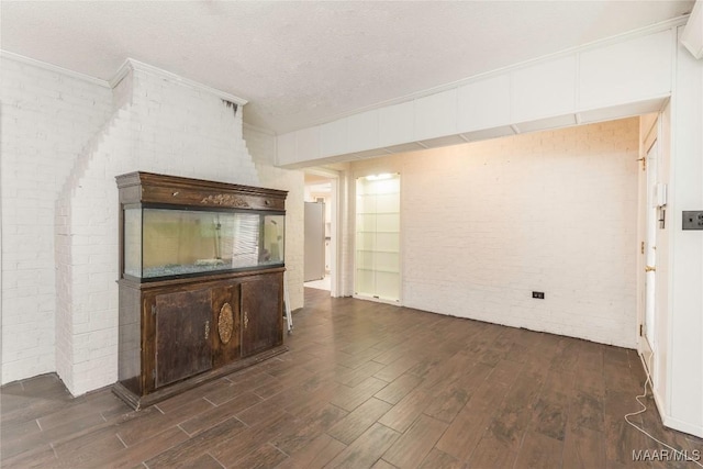 unfurnished living room with brick wall, dark hardwood / wood-style floors, and a textured ceiling