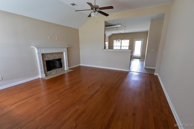 unfurnished living room with lofted ceiling, dark wood-type flooring, a tile fireplace, and ceiling fan