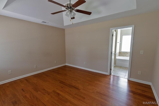 unfurnished room with hardwood / wood-style flooring, ceiling fan, and a tray ceiling