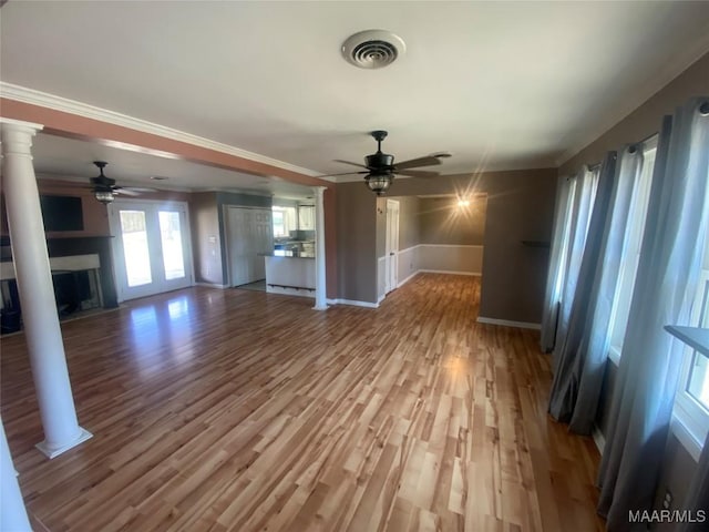 unfurnished living room featuring crown molding, ceiling fan, wood-type flooring, and ornate columns