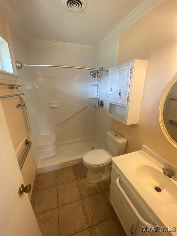 bathroom with crown molding, tile patterned flooring, vanity, toilet, and walk in shower