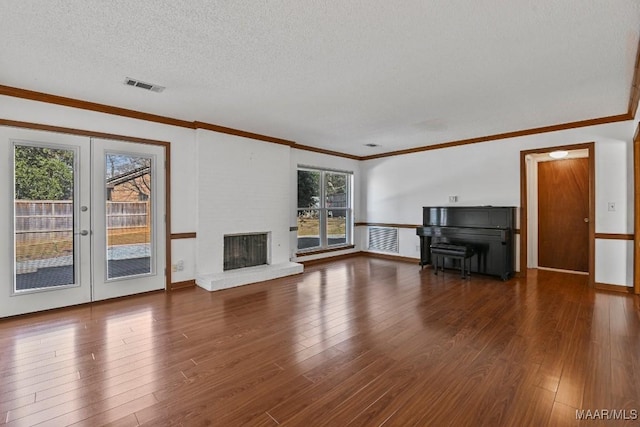 unfurnished living room with dark hardwood / wood-style floors, a fireplace, a textured ceiling, and a wealth of natural light