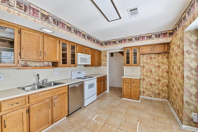 kitchen featuring sink, light tile patterned floors, a textured ceiling, and white appliances