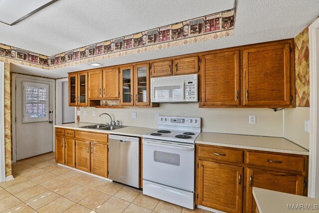 kitchen with sink, white appliances, a textured ceiling, and light tile patterned flooring