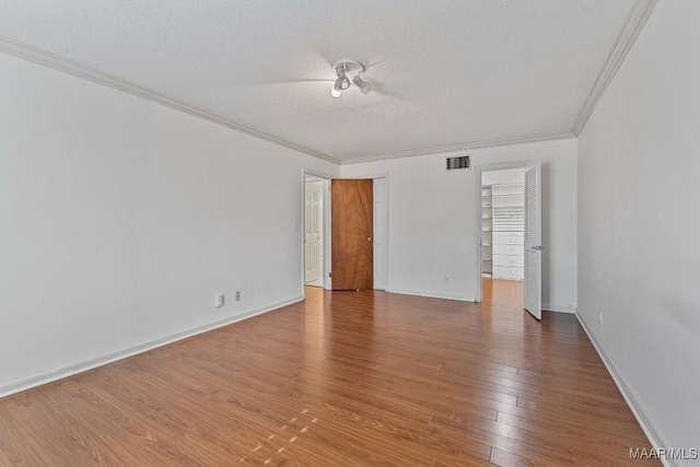 spare room featuring hardwood / wood-style floors, ornamental molding, and a textured ceiling