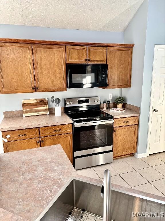 kitchen with stainless steel range with electric cooktop, a textured ceiling, and light tile patterned flooring