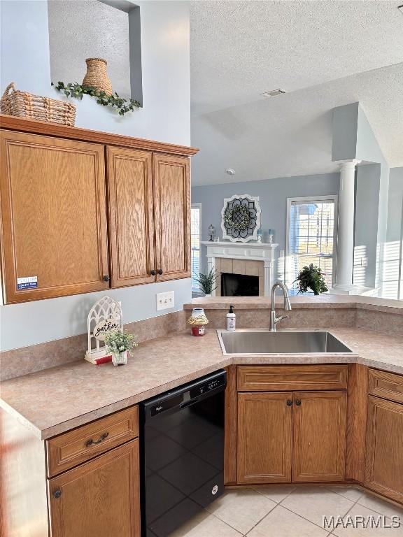 kitchen with black dishwasher, sink, a textured ceiling, and light tile patterned floors