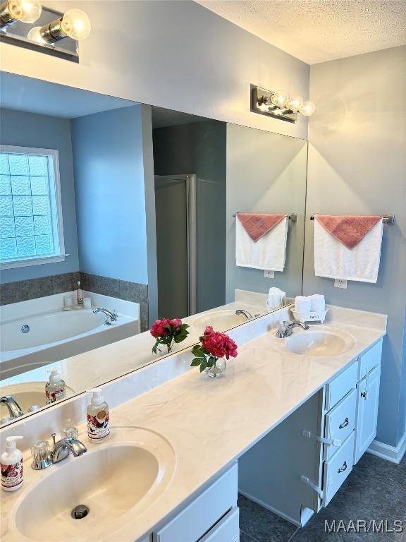 bathroom featuring independent shower and bath, vanity, and a textured ceiling