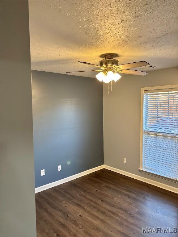 unfurnished room featuring ceiling fan, dark hardwood / wood-style floors, and a textured ceiling