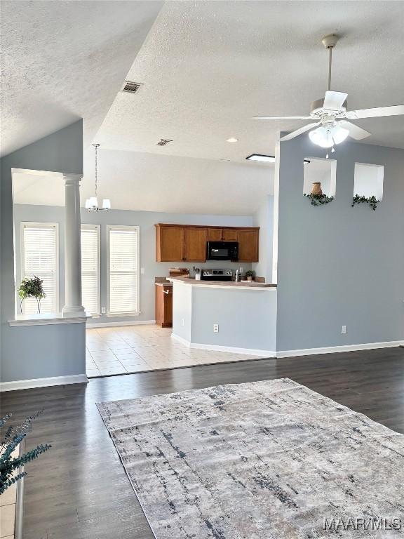 kitchen with vaulted ceiling, decorative columns, hardwood / wood-style flooring, ceiling fan, and a textured ceiling