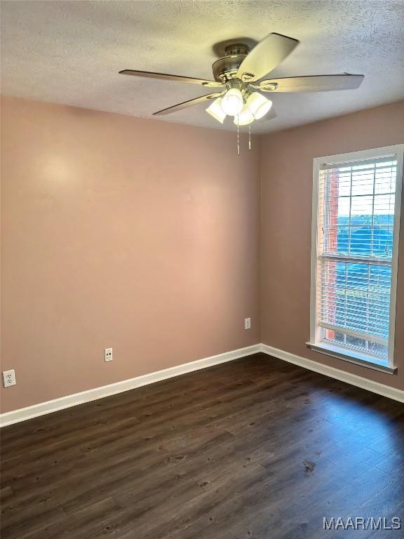 empty room featuring dark hardwood / wood-style flooring, ceiling fan, and a textured ceiling