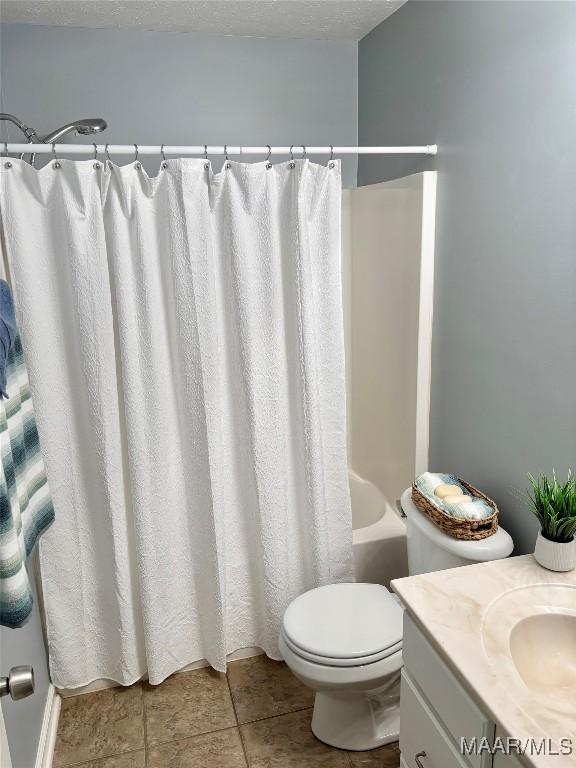 full bathroom featuring shower / bath combination with curtain, vanity, toilet, and a textured ceiling