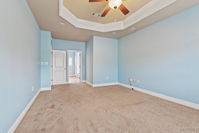 unfurnished bedroom with ornamental molding, light carpet, ceiling fan, and a tray ceiling