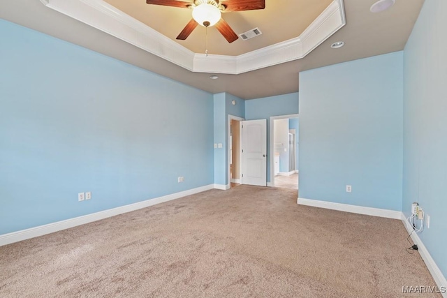 carpeted empty room featuring ceiling fan, ornamental molding, and a tray ceiling