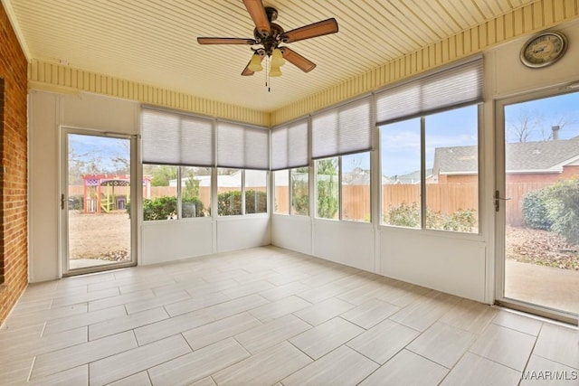 unfurnished sunroom featuring a healthy amount of sunlight, wooden ceiling, and ceiling fan