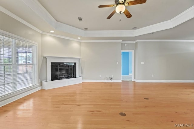 unfurnished living room featuring crown molding, a raised ceiling, ceiling fan, and light wood-type flooring