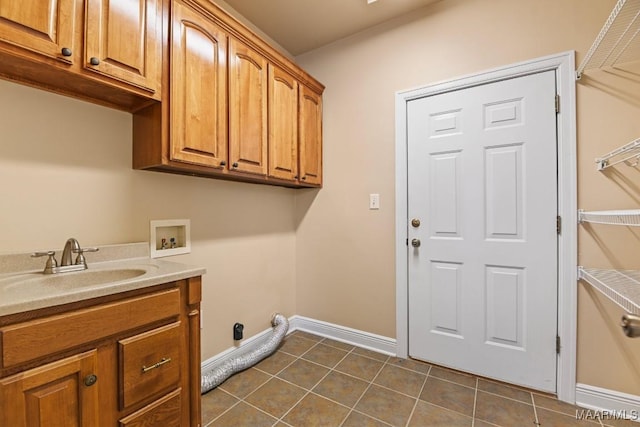 laundry room featuring hookup for a washing machine, sink, cabinets, and dark tile patterned floors