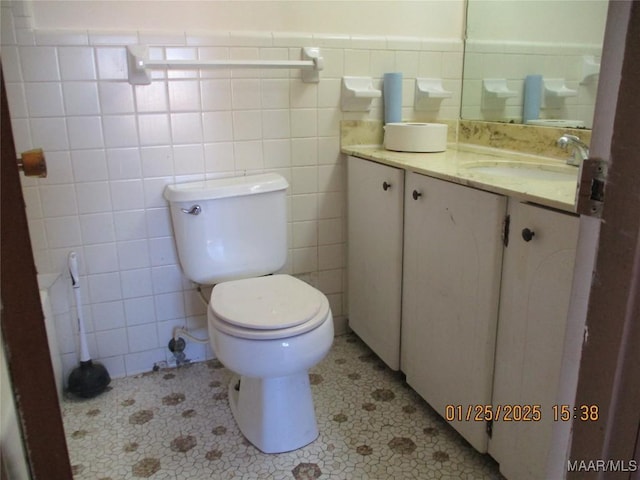 bathroom with vanity, toilet, tile patterned flooring, and tile walls