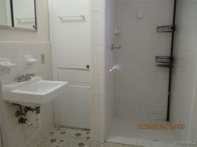 bathroom featuring sink, tiled shower, and tile walls