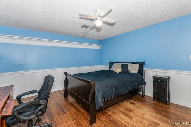 bedroom with dark hardwood / wood-style floors, a textured ceiling, and ceiling fan