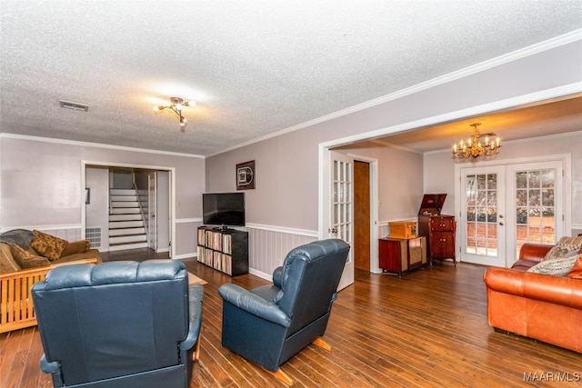 living room with dark hardwood / wood-style flooring, crown molding, a textured ceiling, an inviting chandelier, and french doors