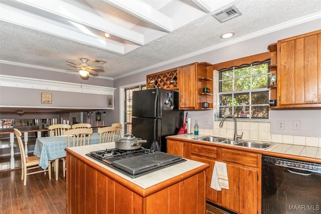 kitchen with sink, ornamental molding, a center island, tile counters, and black appliances