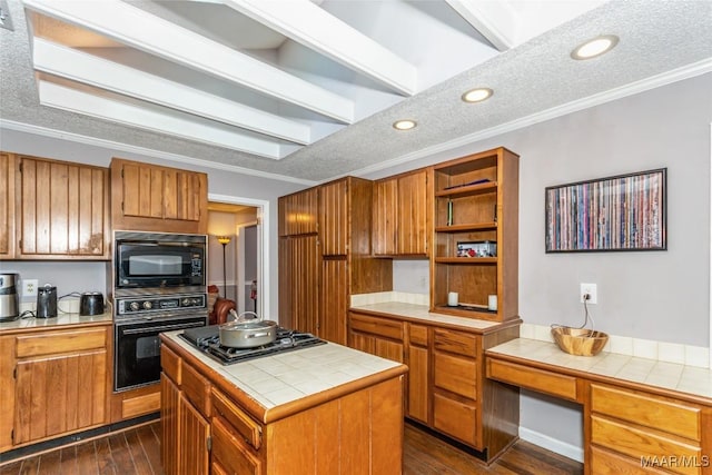 kitchen with crown molding, dark hardwood / wood-style floors, a center island, tile counters, and black appliances