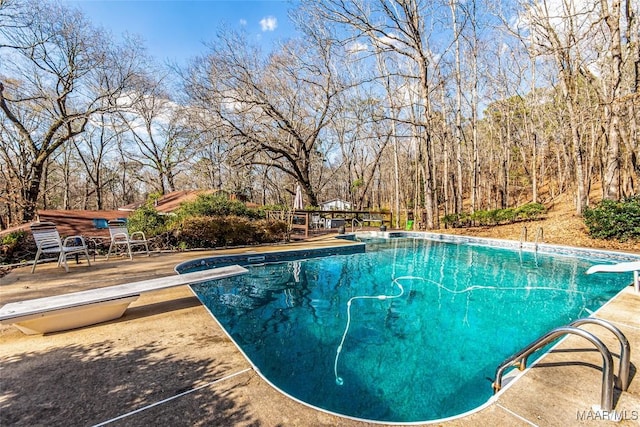 view of swimming pool with a diving board