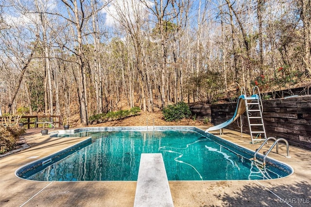 view of pool with a water slide and a diving board